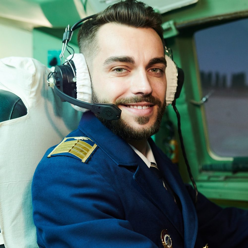 Pilot smiling in the cockpit with headset, ready for flight training.